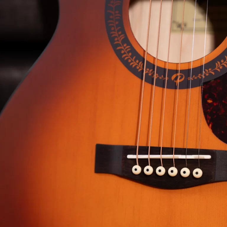 Close-up of an acoustic guitar's soundhole, strings, and bridge with white bridge pins. ขายราคาพิเศษ