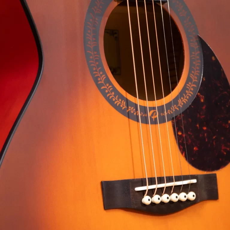 Close-up of an acoustic guitar's soundhole, rosette, and six strings over a sunburst body.] , ขายราคาพิเศษ