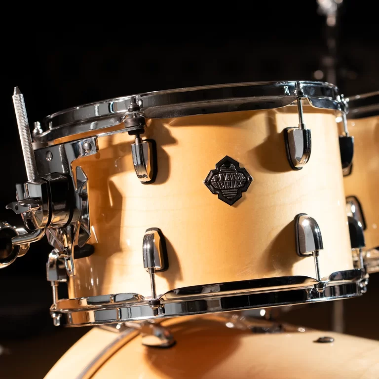 Close-up of a beige snare drum with chrome hardware and a black badge on the shell ขายราคาพิเศษ