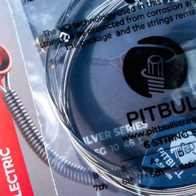 Close-up of a Pitbull guitar string set in plastic packaging, showing coiled steel strings and a red 'Electric' label on the side. ขายราคาพิเศษ