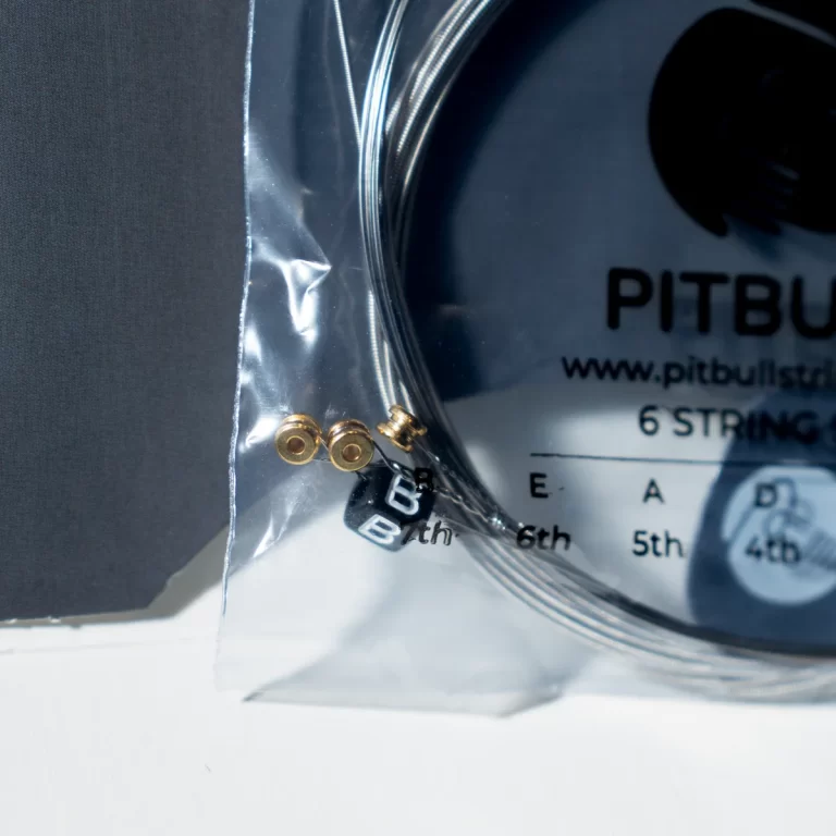 Close-up of a six-string guitar set with brass ball-end tips in clear plastic packaging. ขายราคาพิเศษ