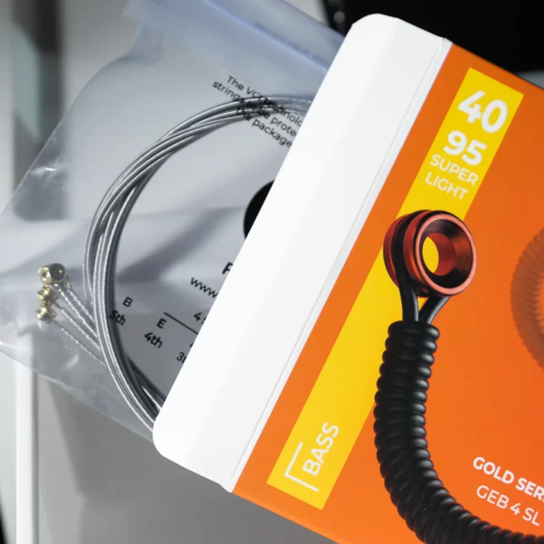 Close-up of a braided silver cable coil next to an orange bass accessory box with 'BASS' and 'SUPER LIGHT' text on yellow panels. ขายราคาพิเศษ