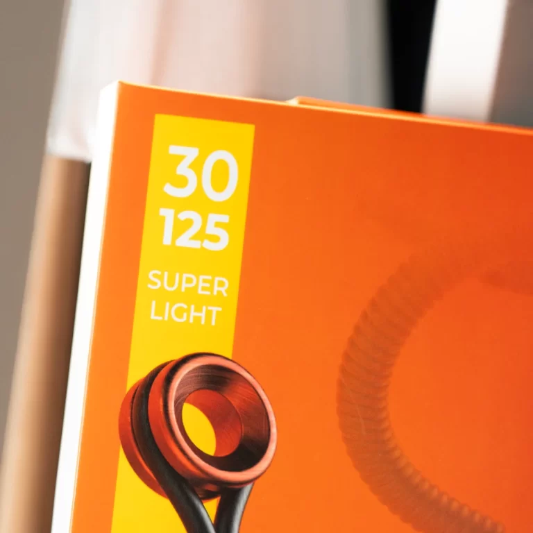 Orange box for headphones with a yellow label reading '30 125 SUPER LIGHT' and a red/black headset in the foreground. ขายราคาพิเศษ