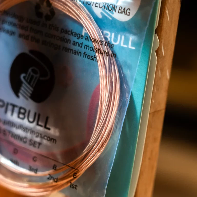 Close-up of a coil set of copper guitar strings in packaging, with part of the product label visible in the background. ขายราคาพิเศษ