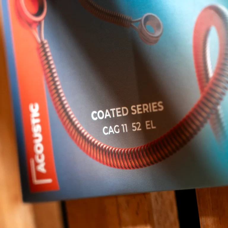 Close-up of product packaging showing the text “COATED SERIES CAG 11 52 EL” with a coiled red cord on a blue background. ขายราคาพิเศษ