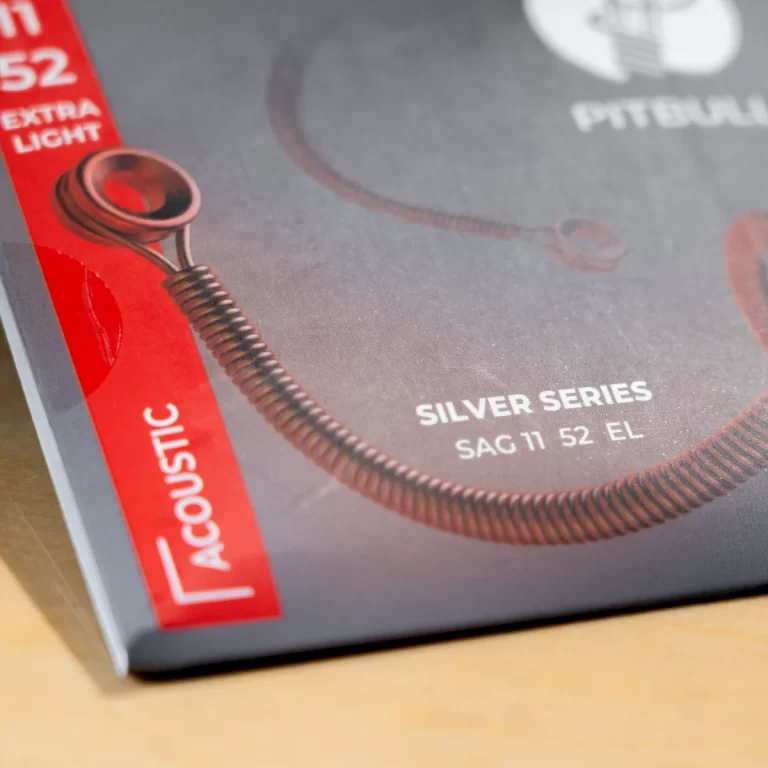 Close-up of guitar-strings packaging with a coiled bronze string and a red 'ACOUSTIC' label, indicating a Silver Series acoustic set (SAG 11 52 EL). ขายราคาพิเศษ