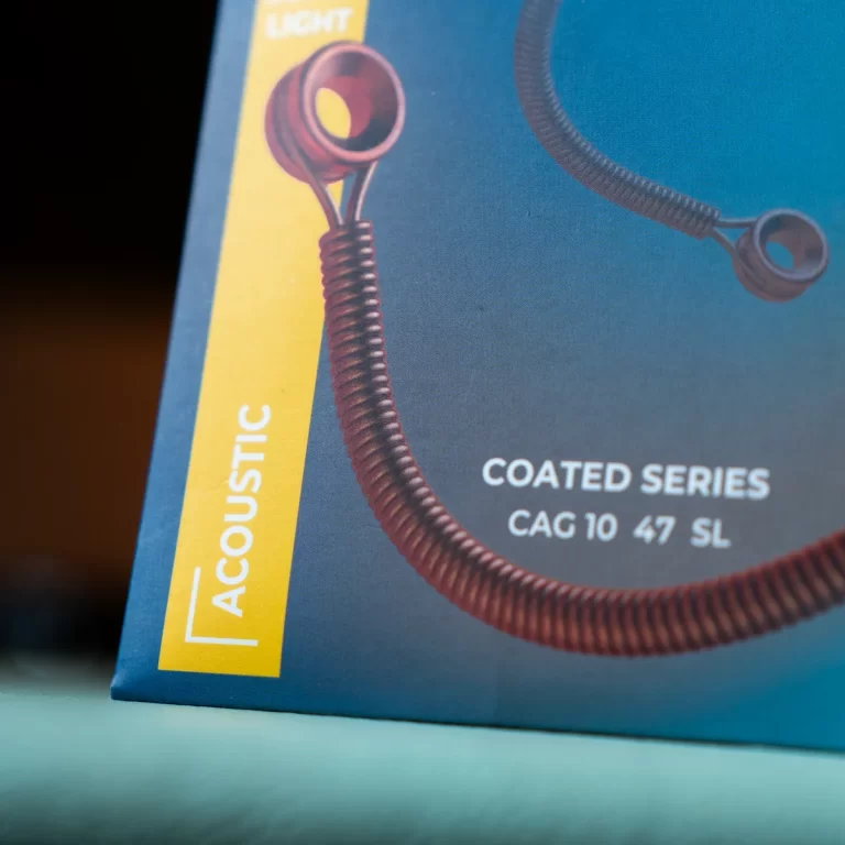 Close-up of a box showing a coiled acoustic cable with a yellow vertical label reading 'ACOUSTIC' and text 'COATED SERIES CAG 10 47 SL' on a blue background. ขายราคาพิเศษ