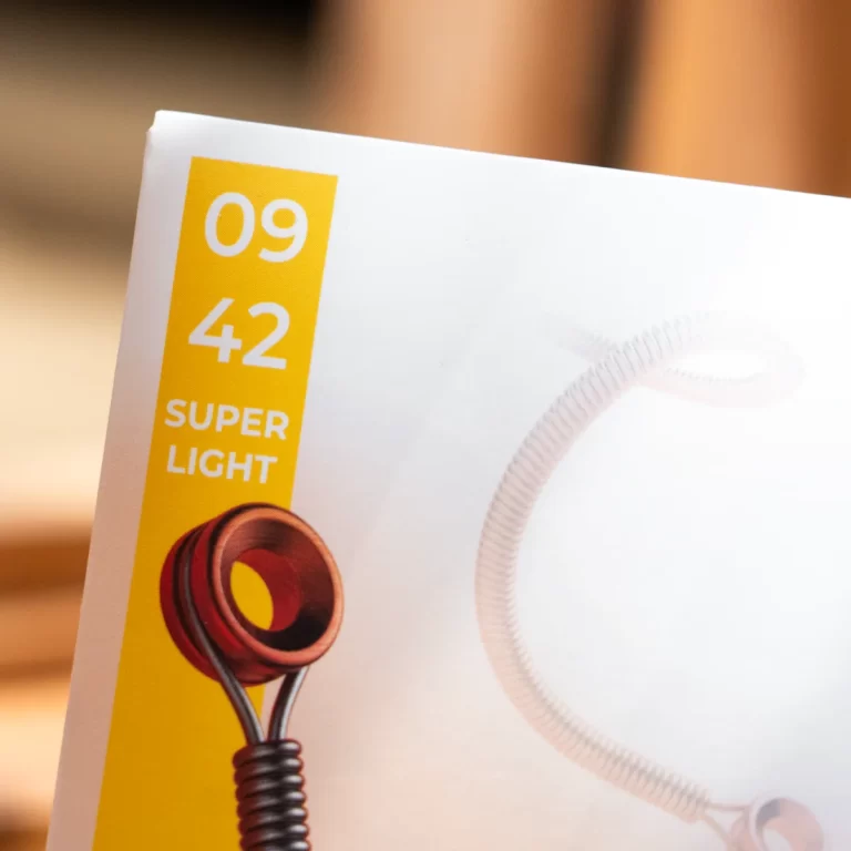 Close-up of product packaging with a vertical yellow label reading '09 42 SUPER LIGHT' and a coiled cord visible on the white surface behind it. ขายราคาพิเศษ