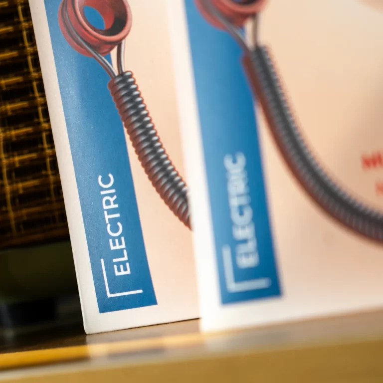 Close-up of two electricity textbooks with blue spines and a coiled wire illustration between them on a shelf. ขายราคาพิเศษ