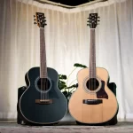 Two acoustic guitars standing upright on guitar cases in a softly lit room with a pale curtain backdrop, one dark blue and one natural wood finish. ลดราคาพิเศษ
