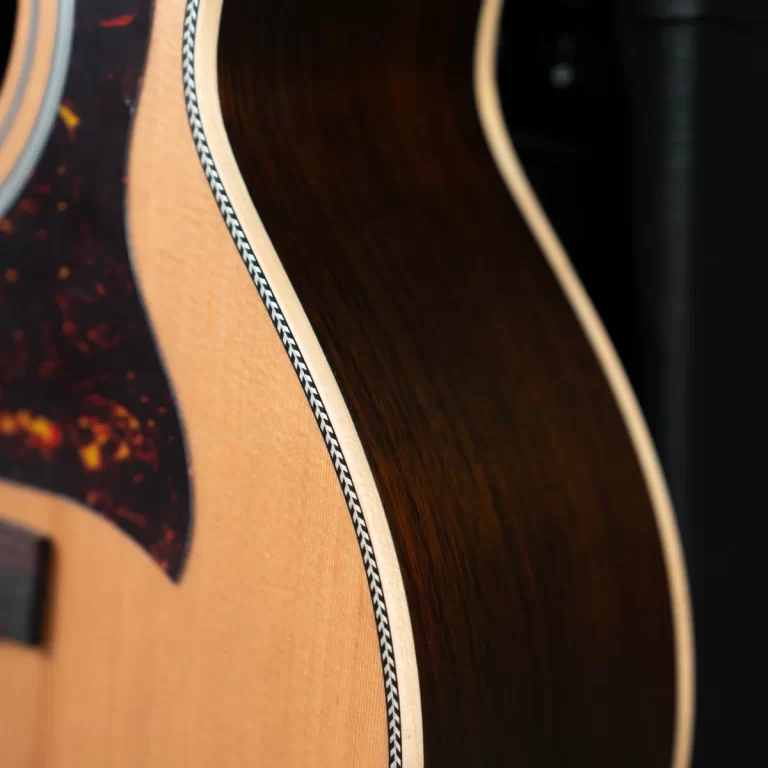 Close-up of an acoustic guitar body showing light top, dark back, and cream binding along the seam. ขายราคาพิเศษ