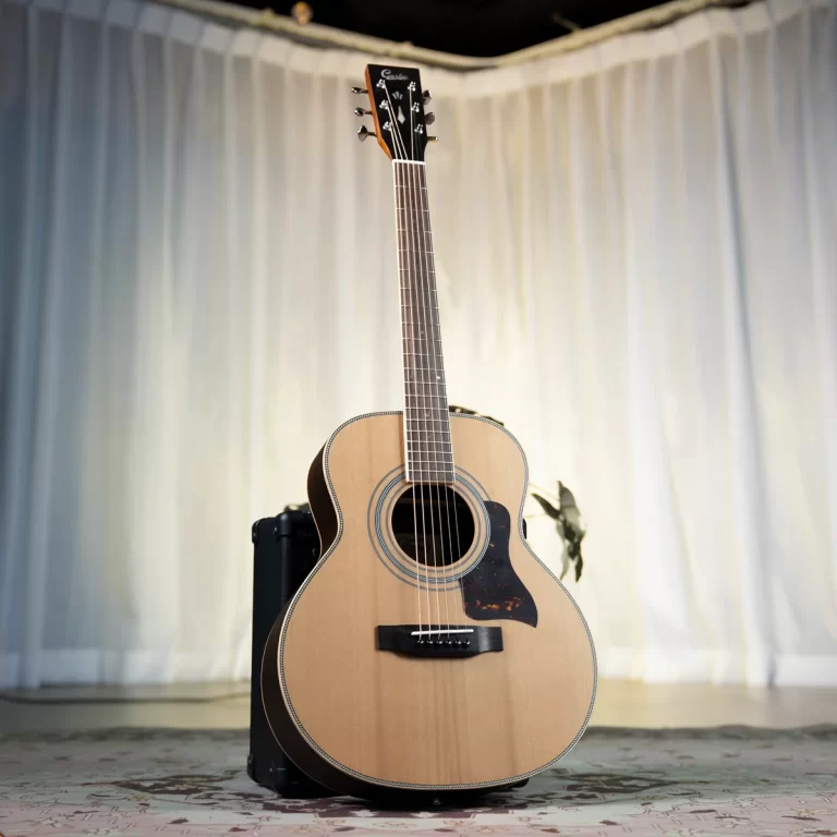 Acoustic guitar on a stand in a softly lit room with white drapes in the background. ขายราคาพิเศษ