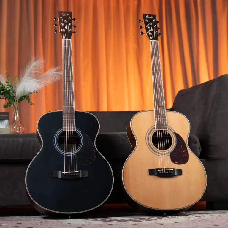 Two acoustic guitars, one black and one natural wood, rest against a dark sofa with orange curtains in the background. ขายราคาพิเศษ