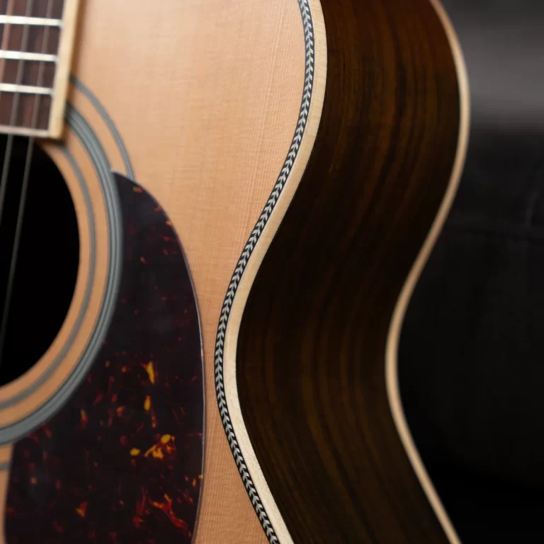 Close-up of an acoustic guitar body, showing the soundhole, tortoiseshell pickguard, and decorative edge binding. ขายราคาพิเศษ