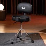 Black padded drum throne with a chrome tripod base on a stage, logo says 'Gusta' on the backrest ลดราคาพิเศษ