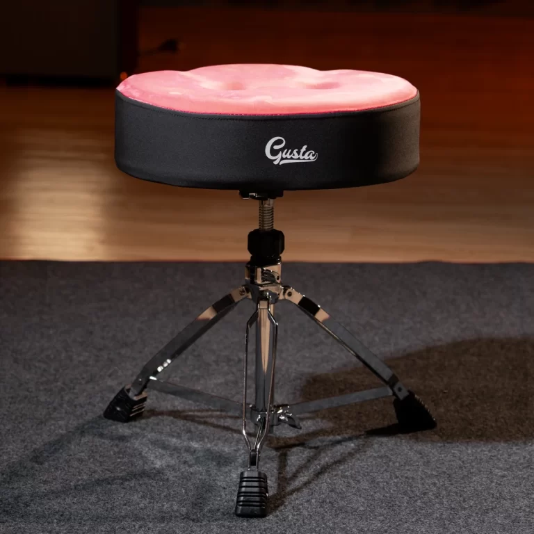 Pink round padded drum throne on a chrome adjustable tripod stand in a rehearsal room, brand 'Gusta'. ขายราคาพิเศษ