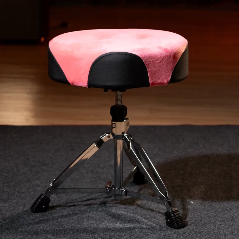 Pink and black padded drum throne on a chrome three‑leg tripod stand, in a music studio setting ขายราคาพิเศษ