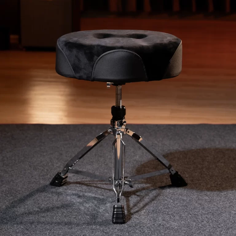 Black drum throne on a chrome tripod with padded seat, in a rehearsal room / stage setting ขายราคาพิเศษ