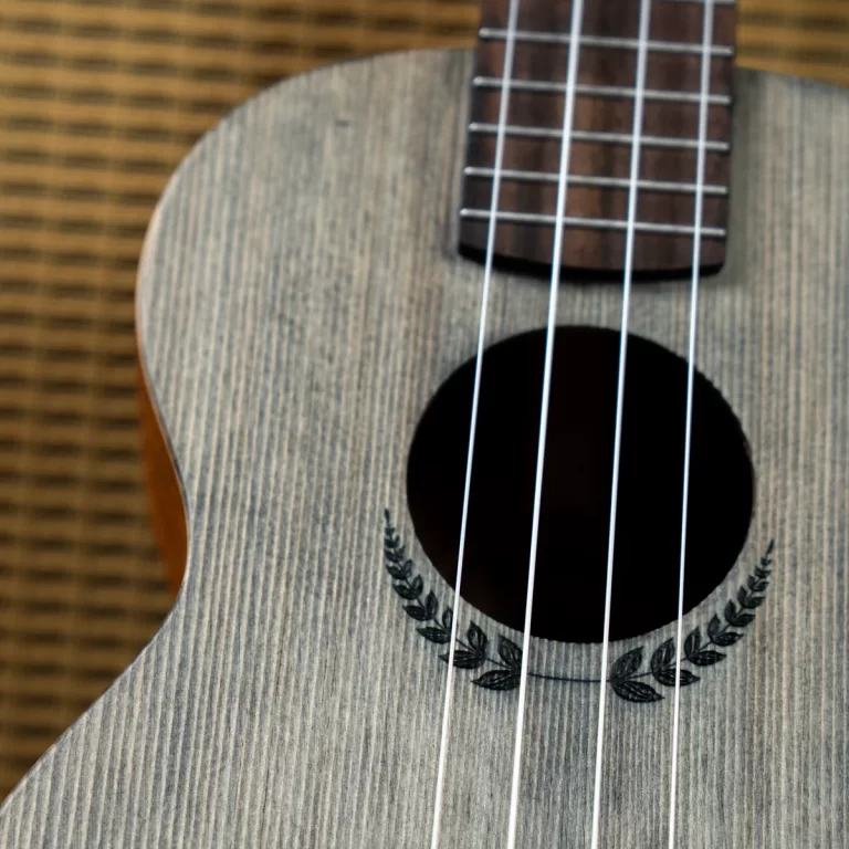 Close-up of a wooden acoustic guitar top, showing the soundhole, strings, and grainy texture. ขายราคาพิเศษ