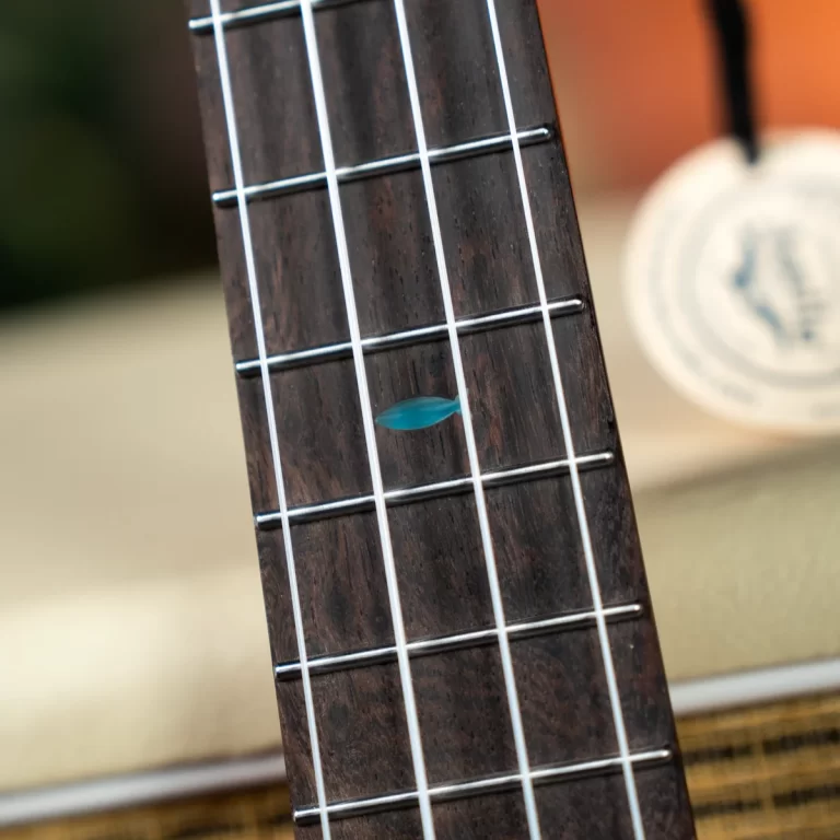 Close-up of a dark wood guitar neck showing frets, white strings, and a blue leaf inlay on the fretboard. ขายราคาพิเศษ