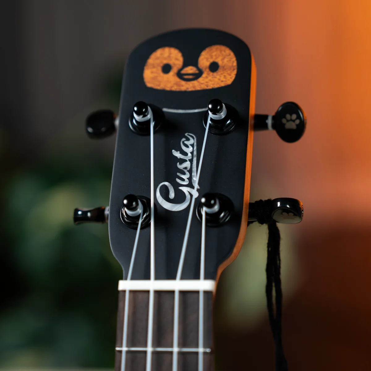 Close-up of a guitar headstock with six tuning pegs, white strings, dark finish, and a white scripted logo on the headstock.