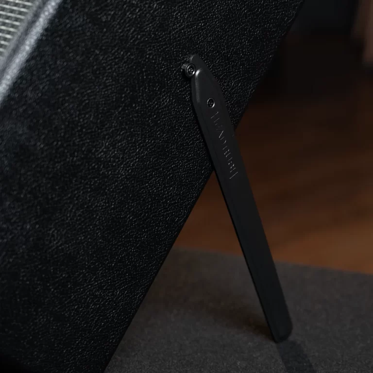 Close-up of a black textured fabric panel with a slim black label attached by a small screw, part of a stand or furniture component. ขายราคาพิเศษ
