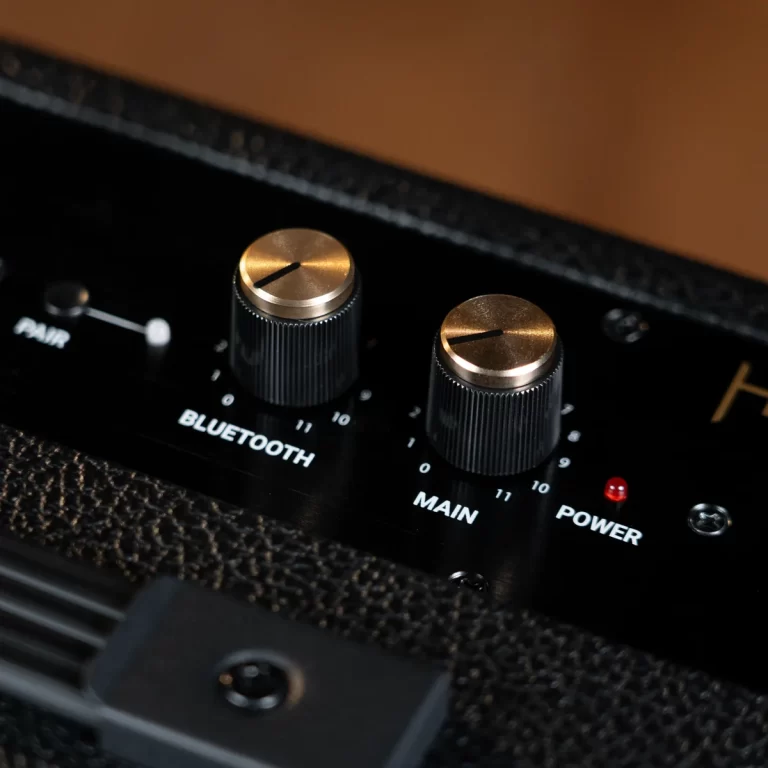 Close-up of a guitar amp control panel with two metal knobs labeled Bluetooth and Main, and a power indicator light nearby ขายราคาพิเศษ