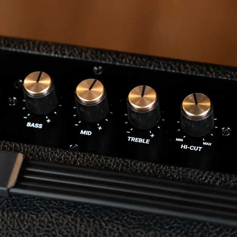 Close-up of a guitar amp panel with brass knobs labeled Bass, Mid, Treble, and Hi-Cut on a black surface. ขายราคาพิเศษ