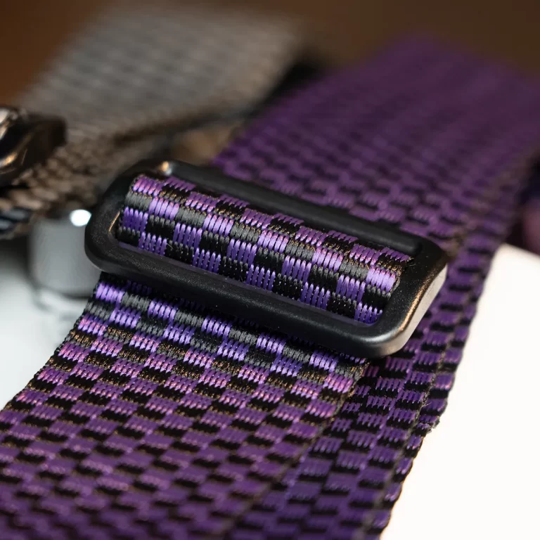 Close-up of a purple and black woven strap with an adjustable plastic buckle on a bag/backpack. ขายราคาพิเศษ