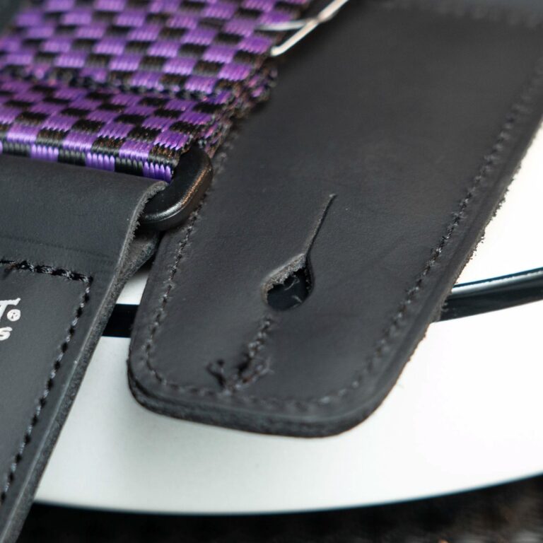 Close-up of a purple and black woven strap threaded through a black leather loop. ขายราคาพิเศษ