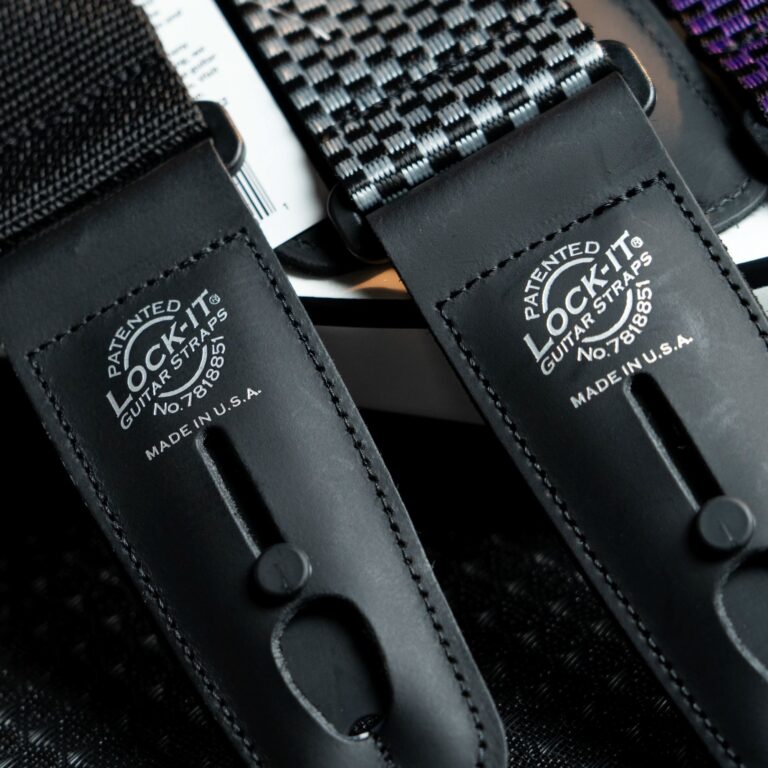 Close-up of a black leather guitar strap with stitched edges and metal rivets. ขายราคาพิเศษ