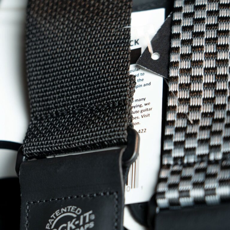 Close-up of a black woven strap with a metal buckle and a white tag peeking out between layers of fabric. ขายราคาพิเศษ