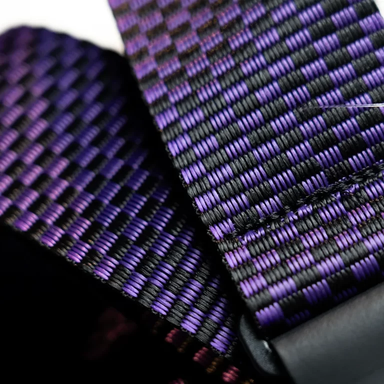 Close-up of purple and black woven strap fabric, showing a checkerboard-like pattern. ขายราคาพิเศษ
