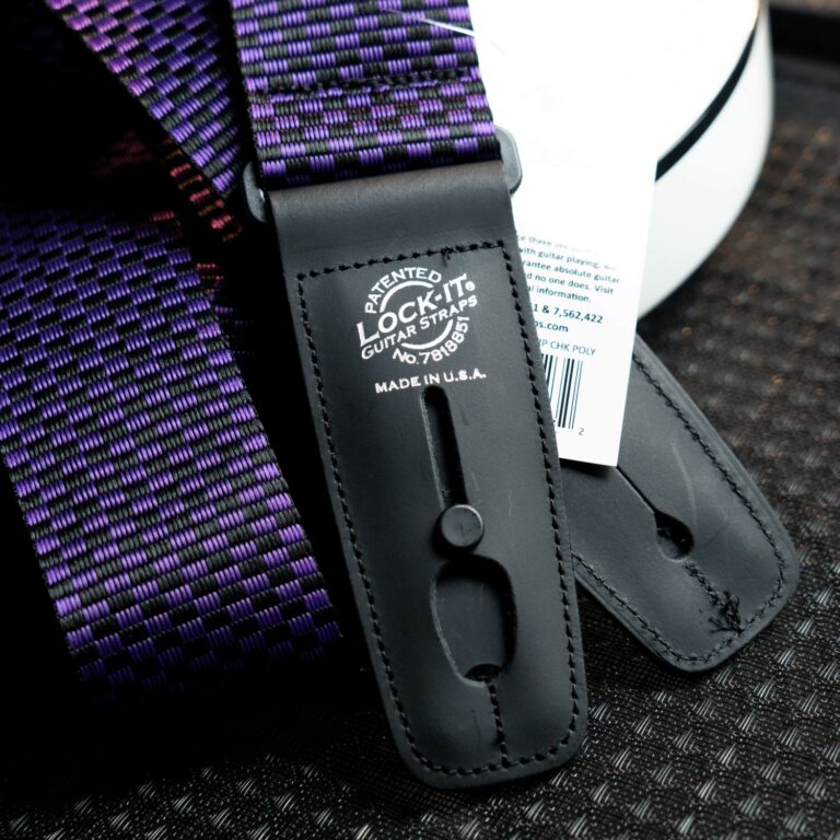 Close-up of a purple and black woven guitar strap with a black leather end piece stamped 'Lock-It' and 'Made in USA'. ขายราคาพิเศษ