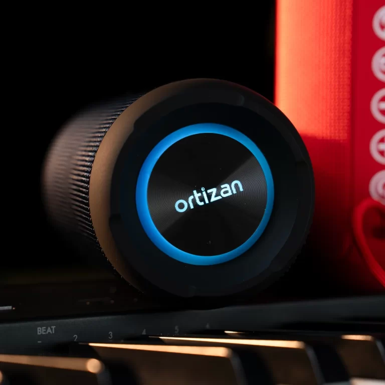 Close-up of a black circular speaker knob with a blue glowing ring and the brand name 'ortizan' in the center. ขายราคาพิเศษ