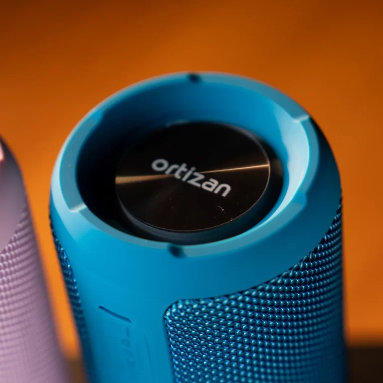 Blue cylindrical portable speaker with a black top disk reading 'ordizan' against an orange backdrop ขายราคาพิเศษ