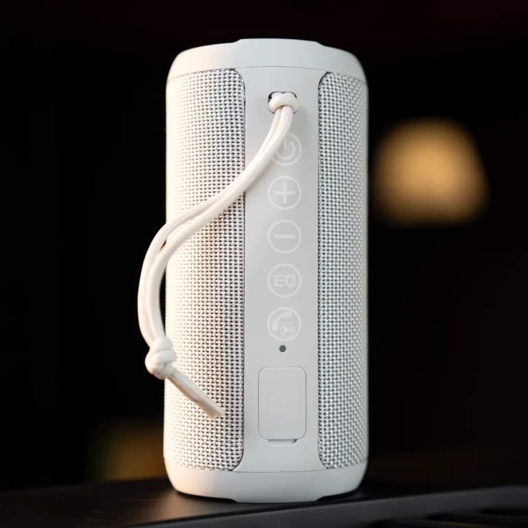 White cylindrical portable Bluetooth speaker with a vertical control panel and fabric mesh sides, including a carrying strap. ขายราคาพิเศษ