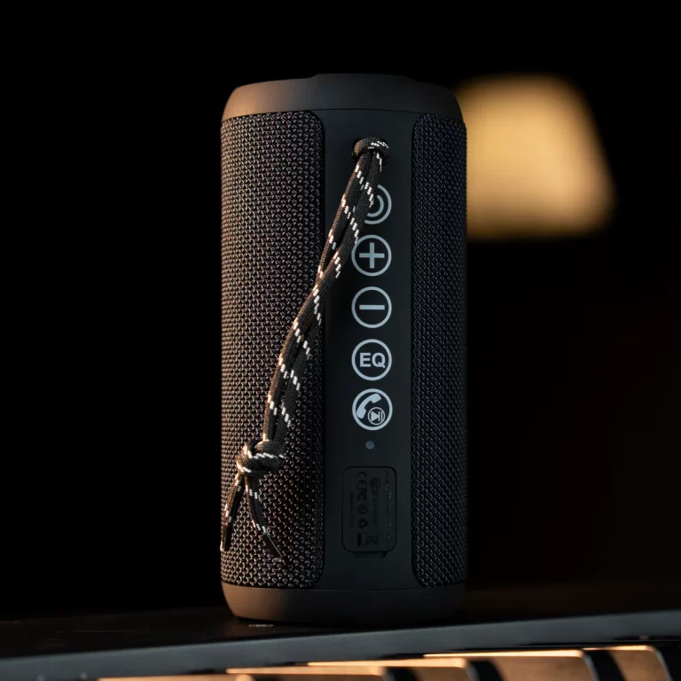 Black cylindrical portable Bluetooth speaker with a striped lanyard and vertical control panel visible on the front. ขายราคาพิเศษ