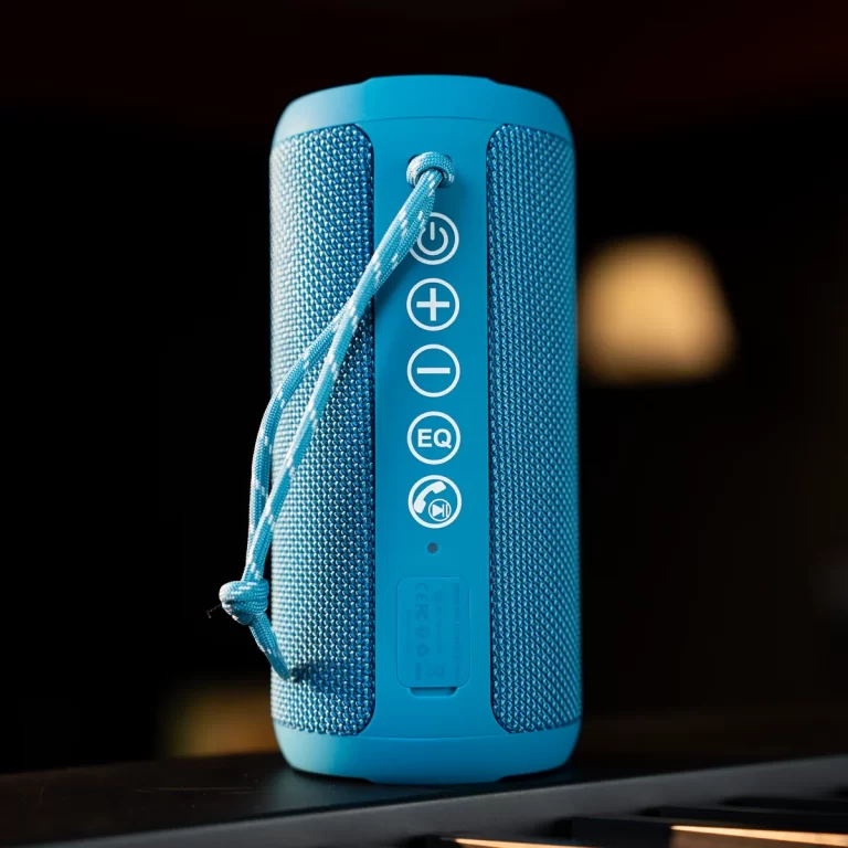 Blue portable Bluetooth speaker with a fabric grille and a built-in strap; side control panel shows power, volume up/down, EQ, and playback icons. ขายราคาพิเศษ