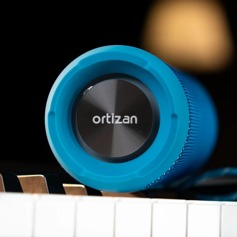 Close-up of bright blue Ortizan headphones resting on piano keys, brand logo visible on the earcups. ขายราคาพิเศษ