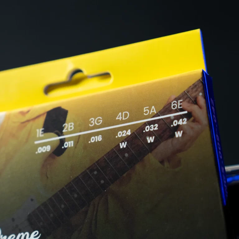 Close-up of a guitar fretboard diagram on packaging, showing string/fret labels and note markings against a yellow background. ขายราคาพิเศษ