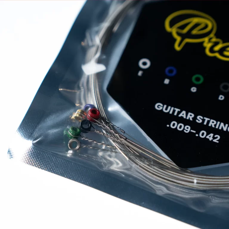 Guitar string set in a sealed plastic bag with a black card showing .009-.042 and colorful ball-end ferrules visible on the left side. ขายราคาพิเศษ