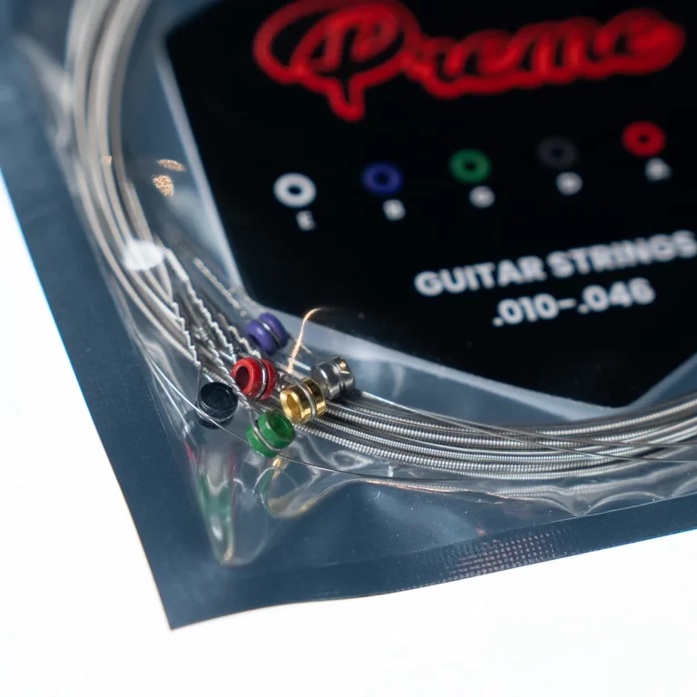 Close-up of guitar strings in a sealed package with colored ball-end pins and a label reading 'GUITAR STRINGS .010-046'. ขายราคาพิเศษ