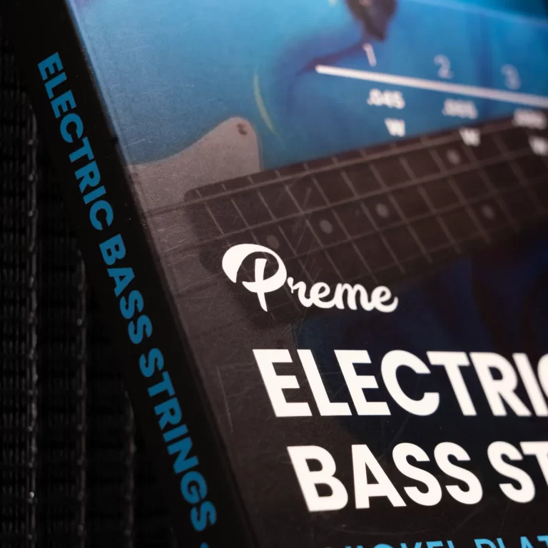 Close-up of a music book cover showing the spine text 'ELECTRIC BASS STRINGS' and a white script logo on a blue patterned panel. ขายราคาพิเศษ