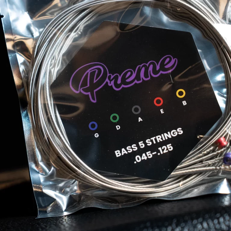 Close-up of a set of bass strings in plastic packaging with the brand 'Prelude' and gauge markings .045-.125 ขายราคาพิเศษ