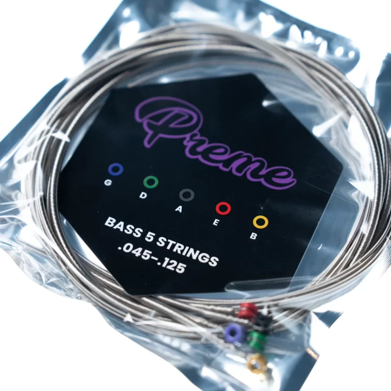 Coiled bass guitar strings in packaging; card shows a purple logo and color-coded letters G, D, A, E, B with 'BASS 5 STRINGS .045-.125'. ขายราคาพิเศษ