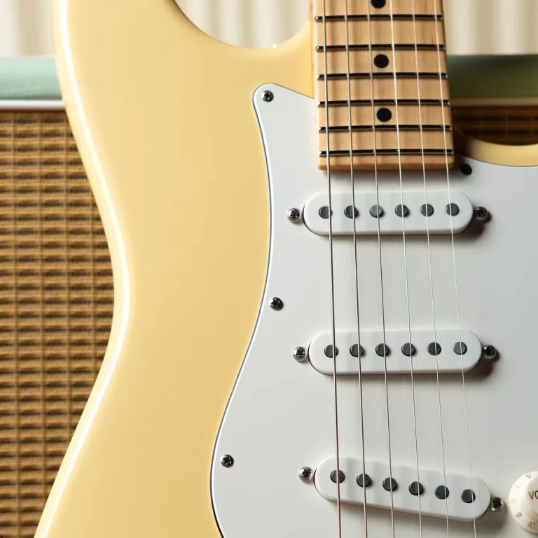 Cream-colored electric guitar close-up: neck with maple fretboard, white pickguard, and three single-coil pickups with six strings. ขายราคาพิเศษ