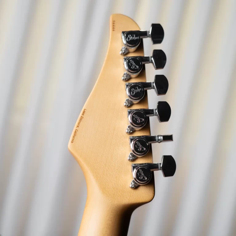 Close-up of a guitar headstock with six chrome tuning pegs on a light wood neck; Suhr logos on the pegs are visible. ขายราคาพิเศษ