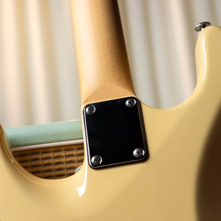 Close-up of a pale yellow electric guitar back, showing the neck plate with four screws and bolt-on neck joint. ขายราคาพิเศษ