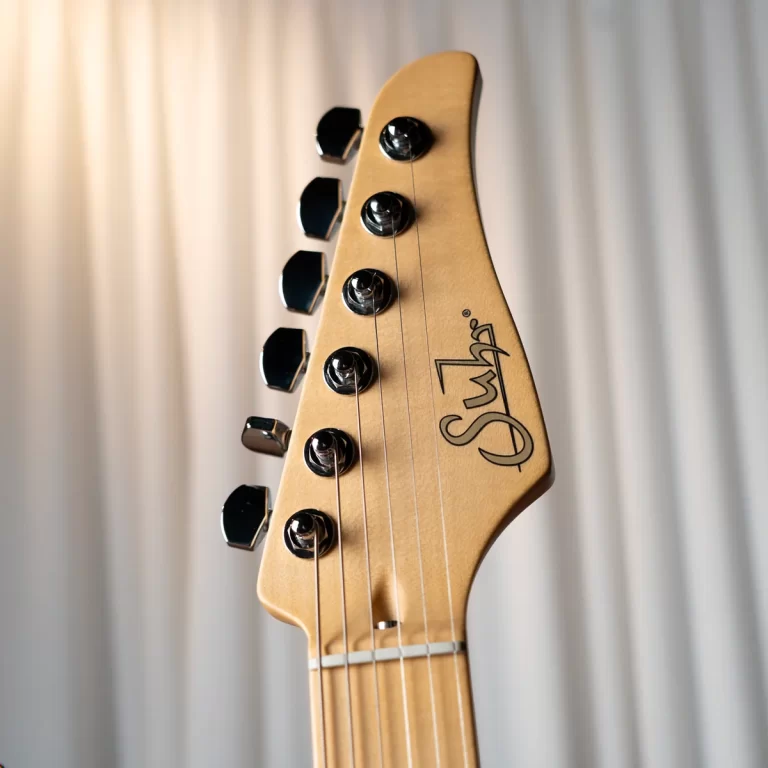 Close-up of a light wood guitar headstock with six chrome tuning pegs and strings visible ขายราคาพิเศษ